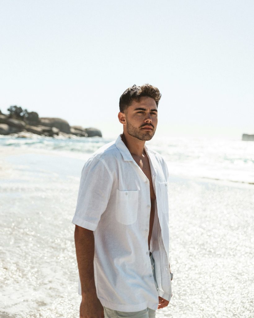 Style plage homme : le guide pour être stylé cet été 3 Homme en chemise légère ouverte sur short de bain, look plage décontracté et soigné