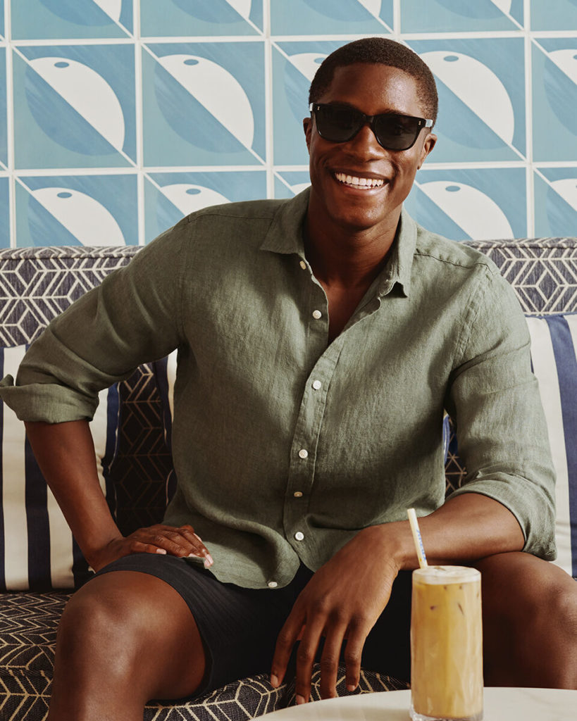 Style plage homme : le guide pour être stylé cet été 5 Homme souriant en chemise de lin kaki et short marine, look plage homme décontracté et élégant