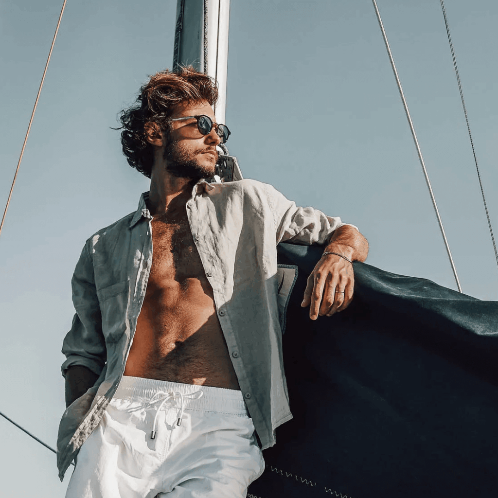Style plage homme : le guide pour être stylé cet été 4 Homme en chemise de lin ouverte sur short de bain blanc, style plage homme élégant